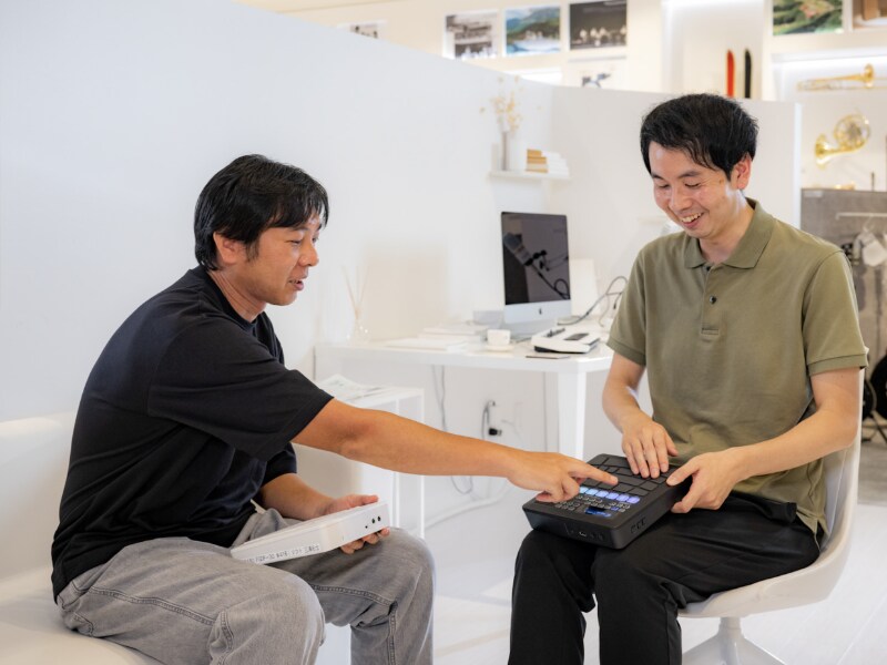 Yamashita and Miura conversing while looking at FGDP on their lap