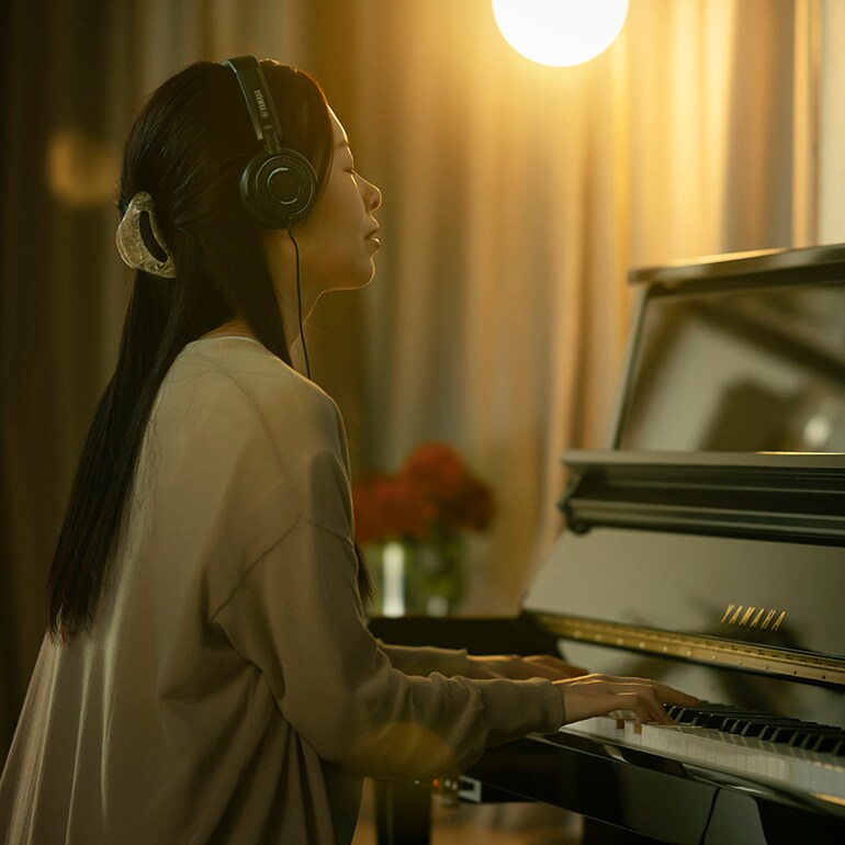 ヘッドホンによるピアノの消音演奏を楽しむ女性