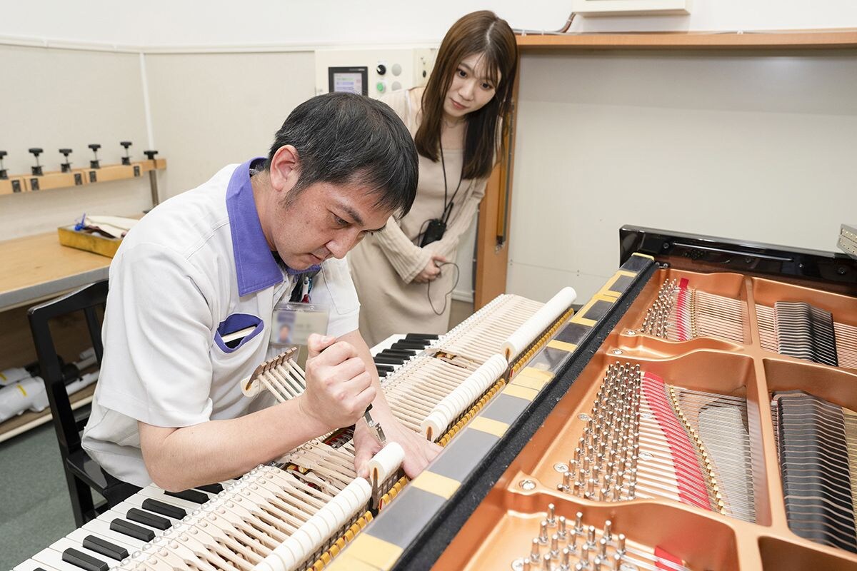 グランドピアノ製造工程を見学する南さん