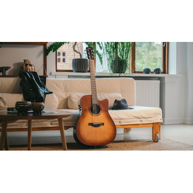 ソファの上でバッグのそばに置かれたTAG3 Cアコースティックギター。