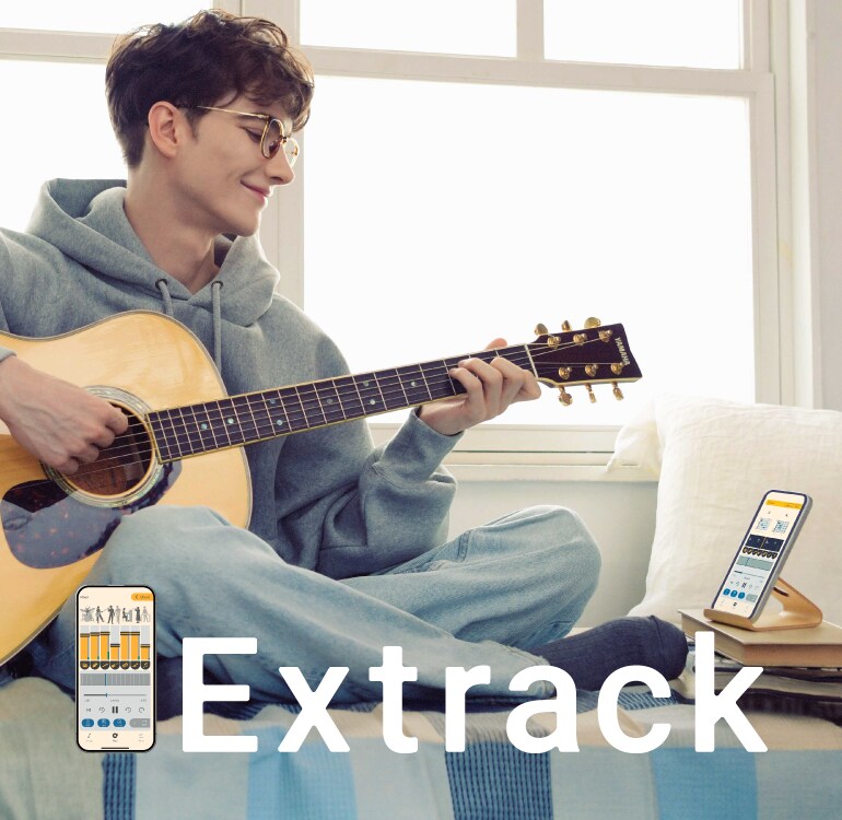 ソファに座り楽器アプリ「Extrack（エクストラック）」でセッションしながらギター練習を楽しむ男性